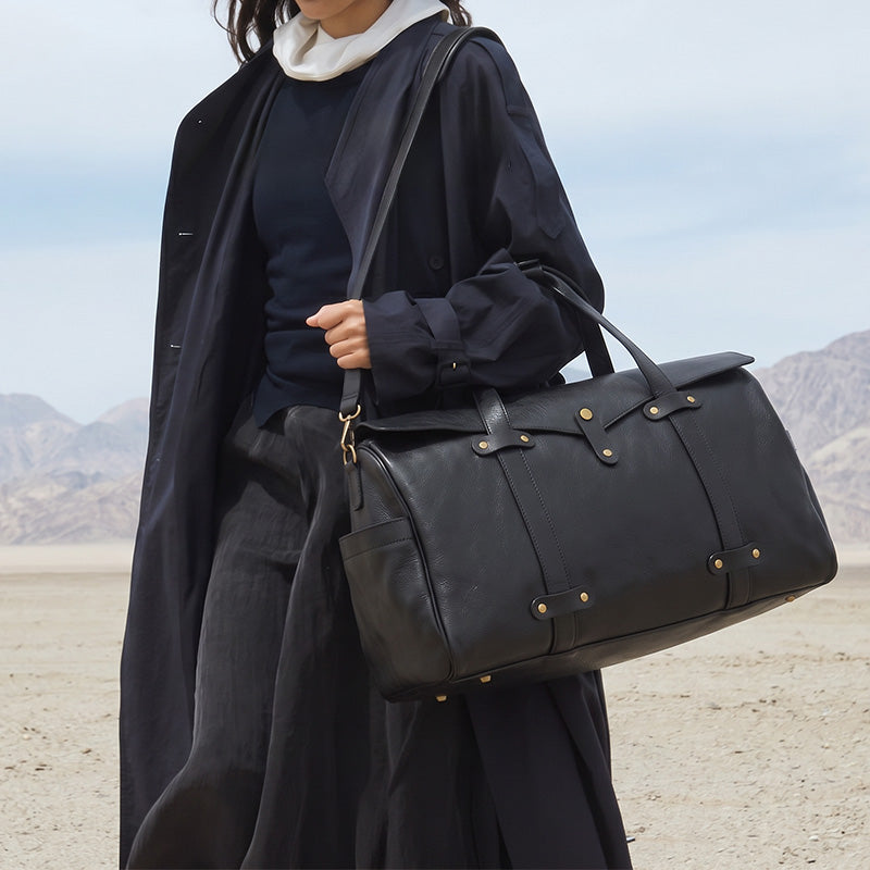 Black vegetable-tanned leather duffle bag with gold hardware and dual top handles