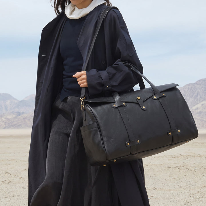 Black vegetable-tanned leather duffle bag with gold hardware and dual top handles