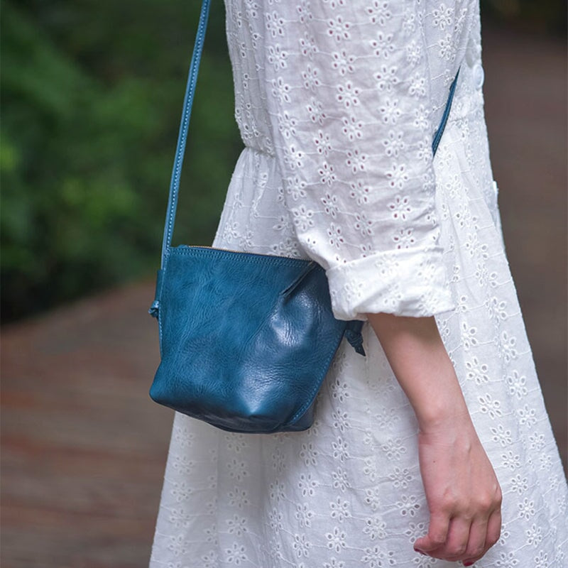 Woman wearing a soft vegetable tanned leather dumpling bag in teal blue crossbody