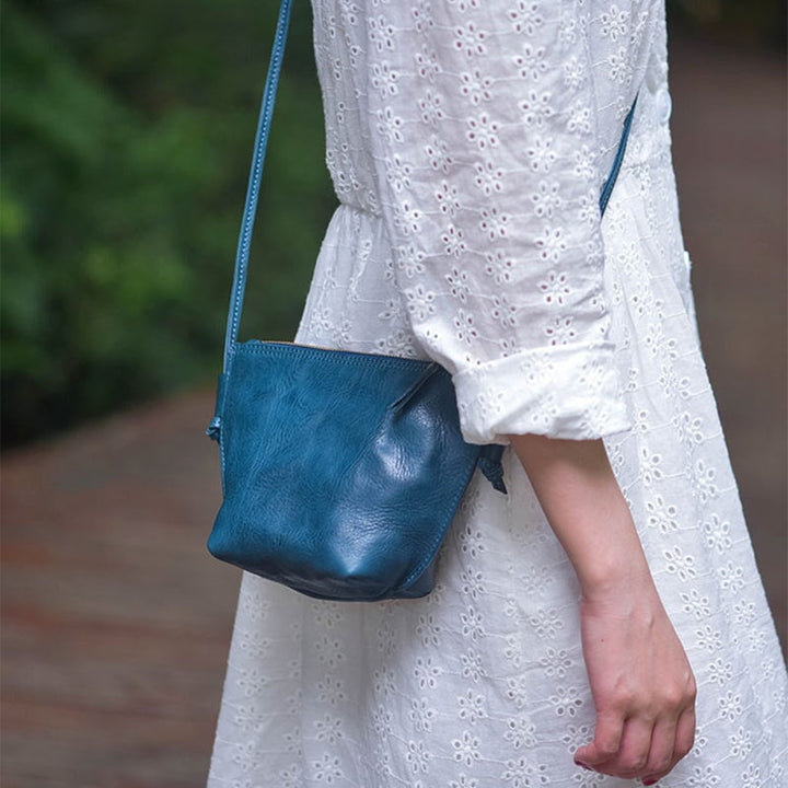 Woman wearing a soft vegetable tanned leather dumpling bag in teal blue crossbody