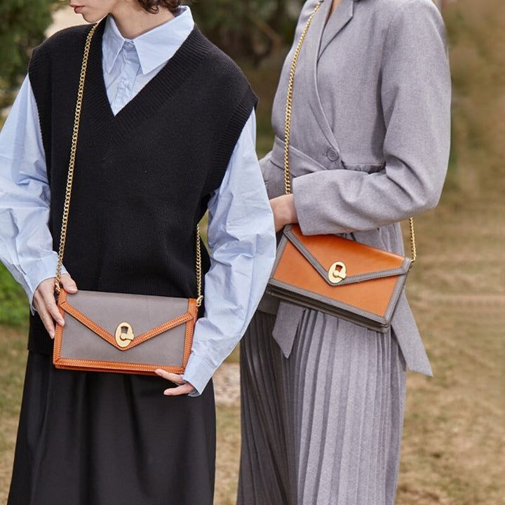 Two women carrying vegetable tanned leather envelope clutches with gold chain in yellow and gray