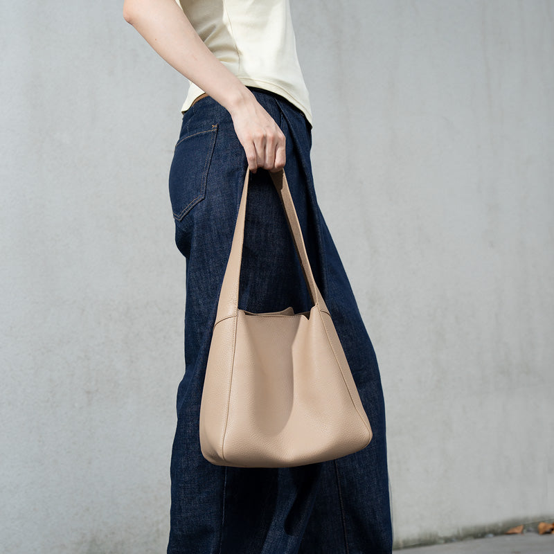 Woman carrying a beige full grain leather hobo shoulder bag