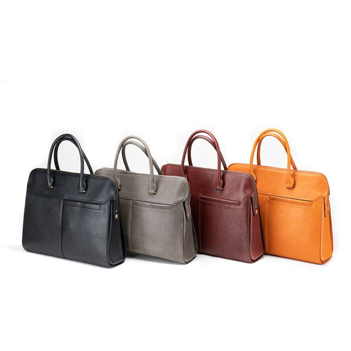 Four vintage leather laptop briefcases in black, grey, brown and yellow on white background
