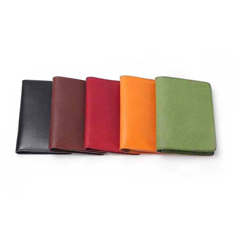 Vegetable tanned leather passport holder in five colors — black, brown, red, yellow, and green.