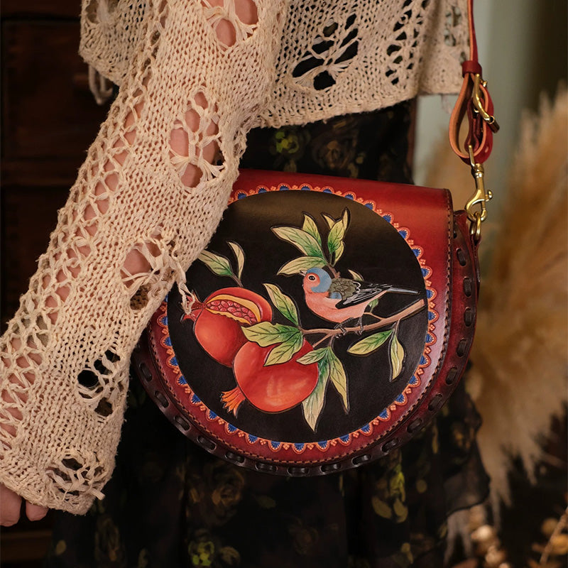Woman carrying a hand-carved leather saddle bag with bird and pomegranate design