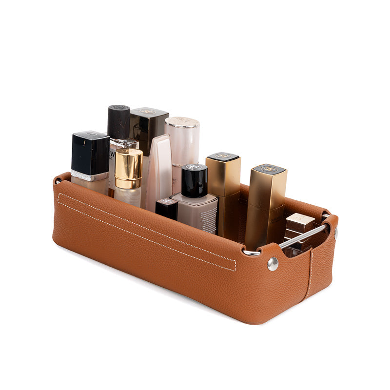 Brown leather valet tray holding skincare and makeup bottles on a vanity