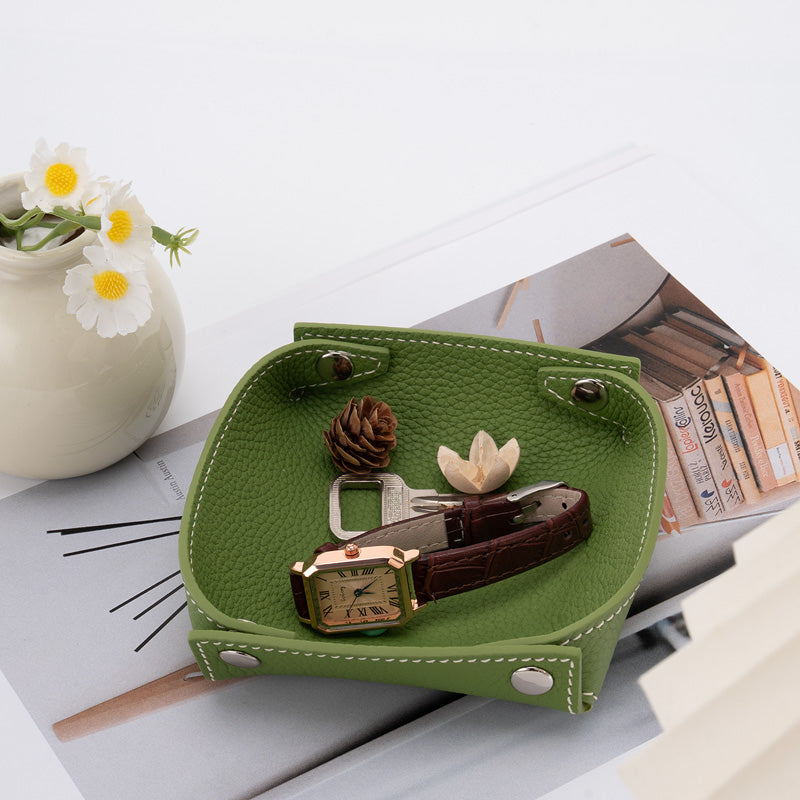 Foldable pebbled cowhide leather valet tray in green with snap corners, holding a watch and keys