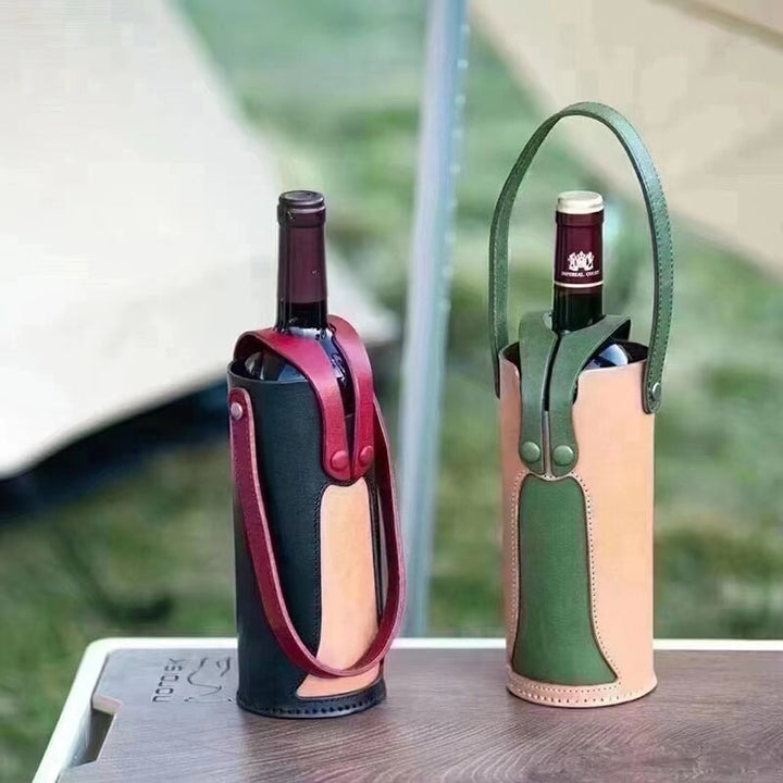 Two handmade leather wine bottle carriers in black-red and green at an outdoor picnic