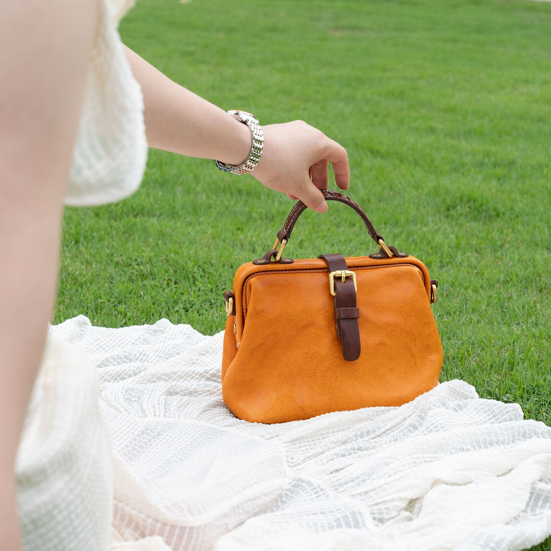 Woman holding a mini vintage leather doctor bag in sunset yellow at a picnic