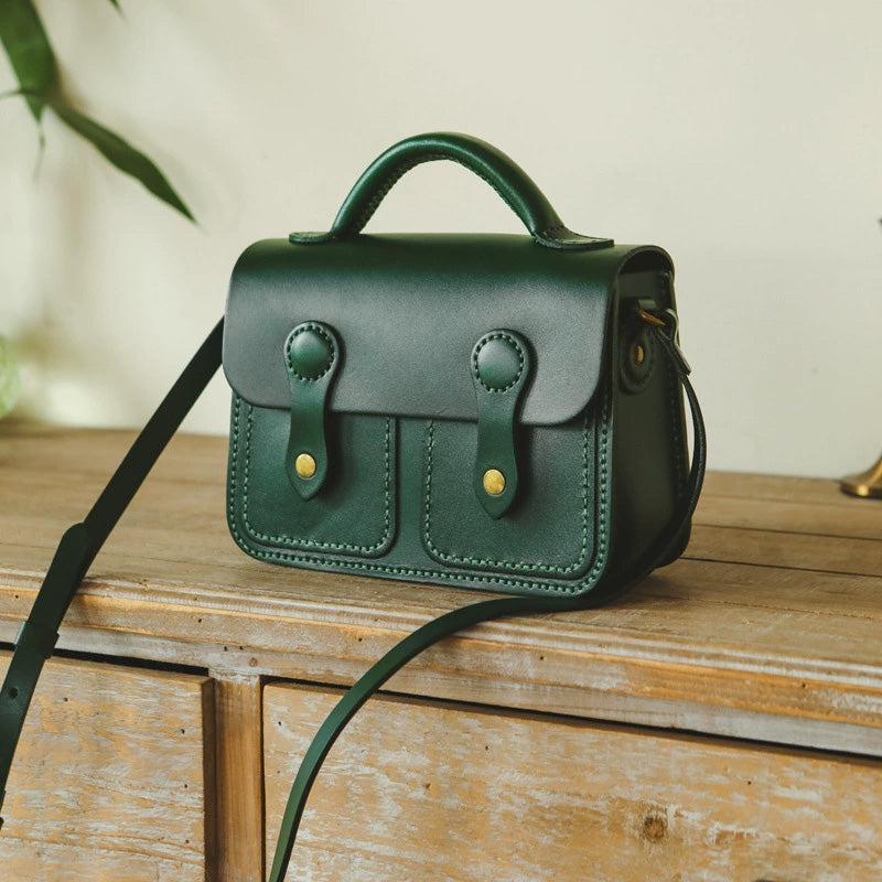 Dark green leather satchel crossbody bag with top handle and brass hardware