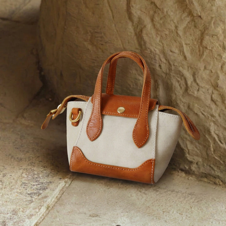 Mini canvas tote bag with tan leather trim and brass hardware, handheld style