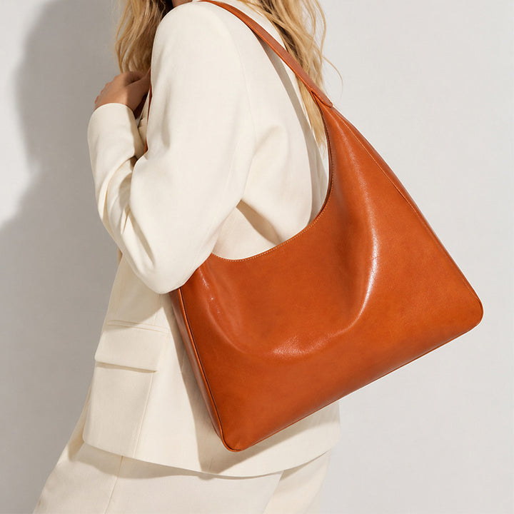 Orange vegetable tanned leather hobo bag with structured silhouette and back zip pocket 