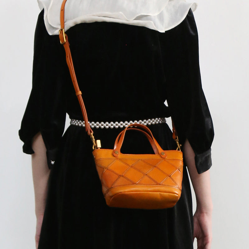Orange woven leather mini handbag with a top handle and crossbody strap.