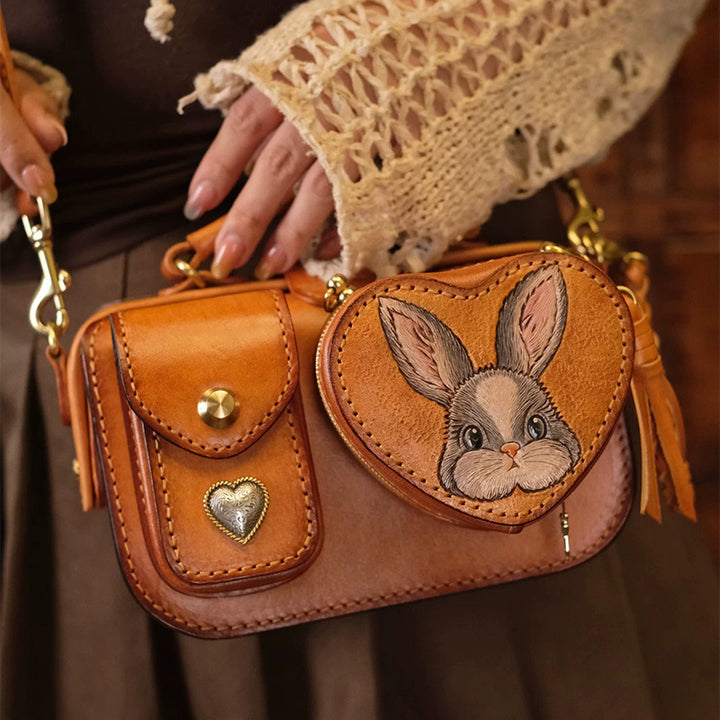 Brown leather camera bag with a rabbit heart pouch, shown with its shoulder strap.