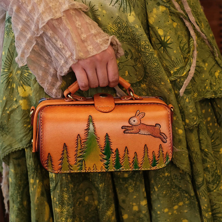 Model holding a vegetable tanned leather doctor bag with a carved rabbit and forest design.