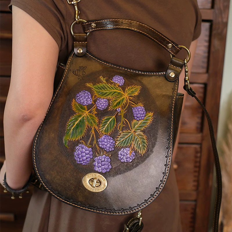 Brown tooled leather convertible backpack with raspberry artwork and a top handle.