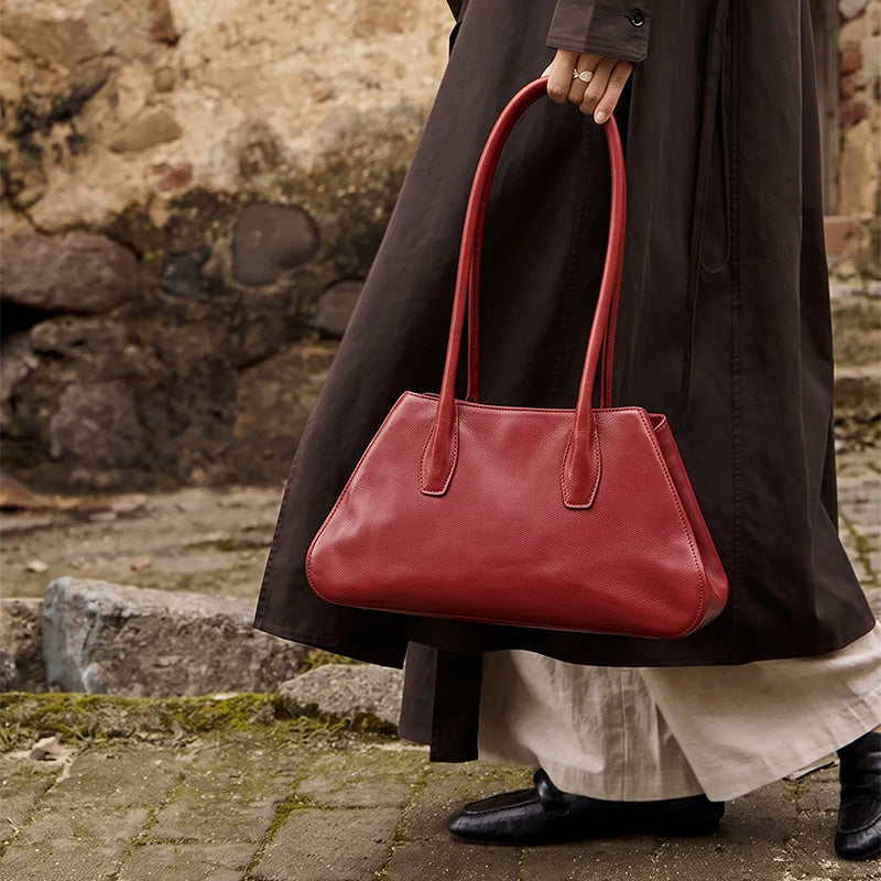 Model holding a red leather east-west shoulder bag with long double handles.