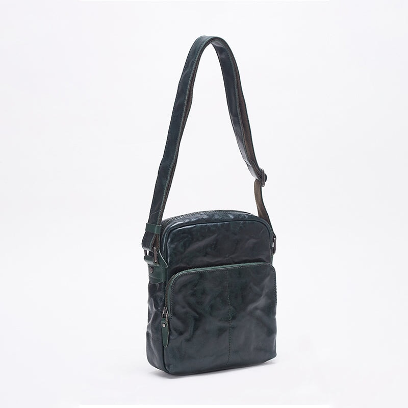 Dark green veg tan leather crossbody messenger bag with front zip pocket and adjustable strap