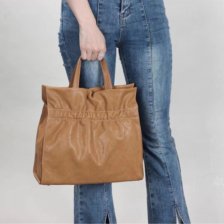 Woman carrying a ruched vegetable tanned leather tote bag in apricot