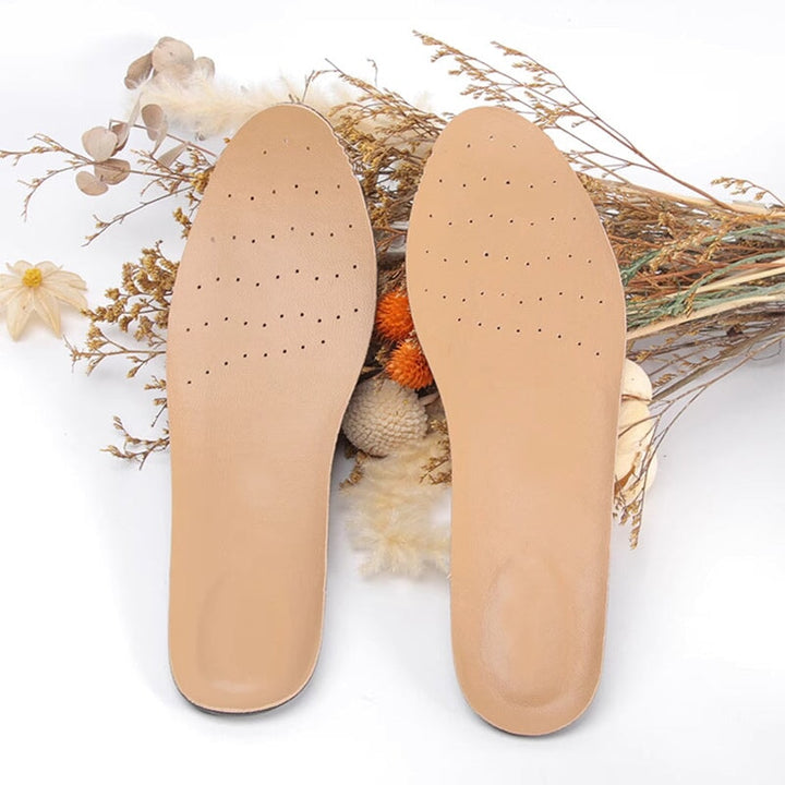 A pair of beige perforated sheepskin insoles with breathable holes for all-day comfort