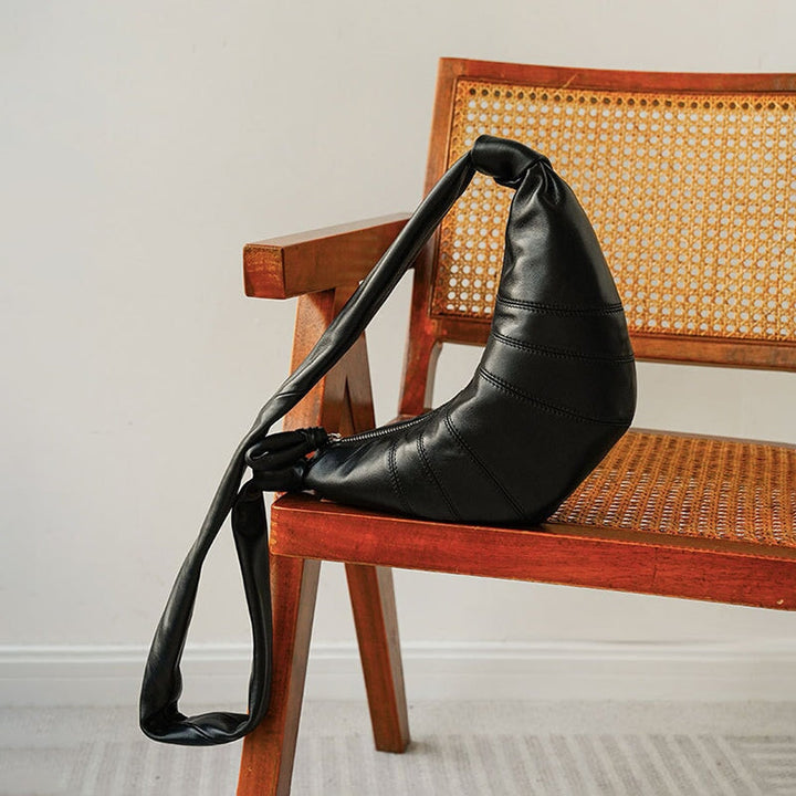 Black sheepskin leather dumpling bag with puffy crescent silhouette and twisted strap.