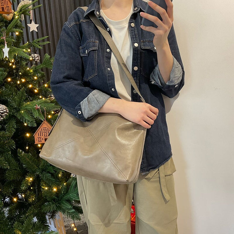 Woman carrying a large slouchy vegetable tanned leather shoulder bag in Morandi gray