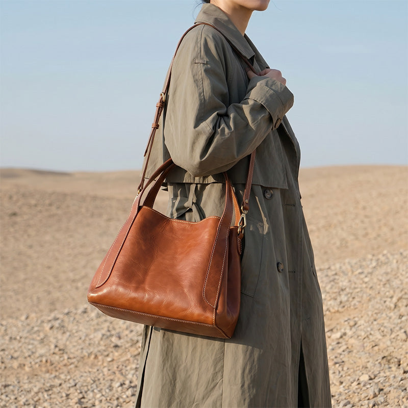 Woman carrying a small vegetable-tanned leather bucket bag in honey brown crossbody style