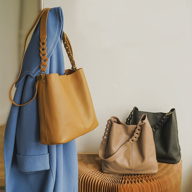 Soft leather bucket bags in yellow, beige and black with braided strap in warm interior setting