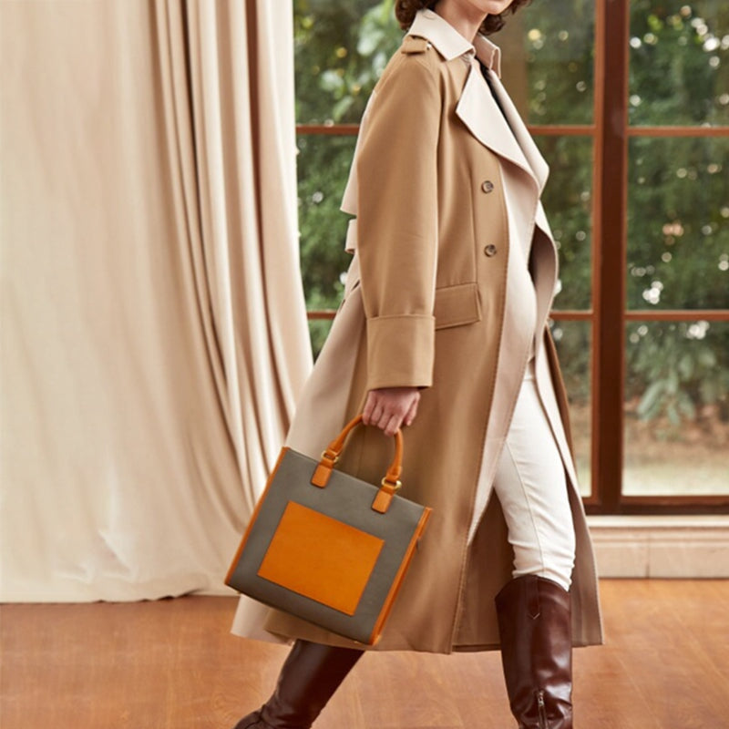 Woman carrying a structured leather tote bag in yellow and gray color block