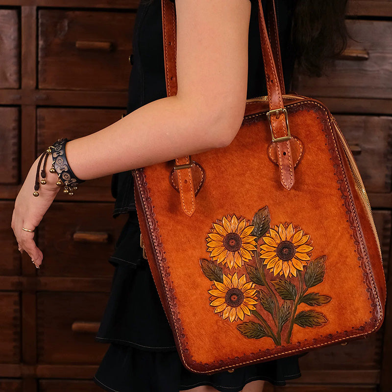 Woman carrying a honey-brown leather tote bag with three hand-tooled sunflowers.