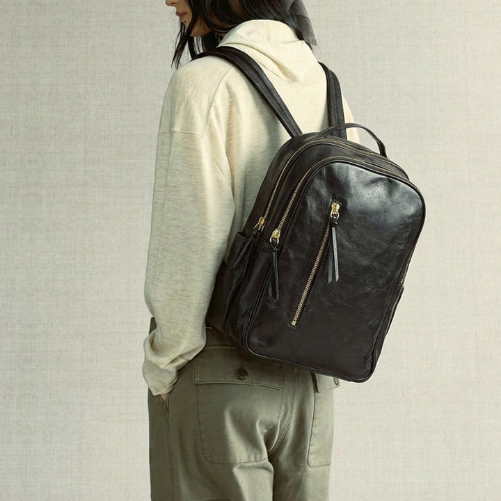 Black vegetable-tanned full-grain leather backpack with gold-tone zippers and adjustable straps