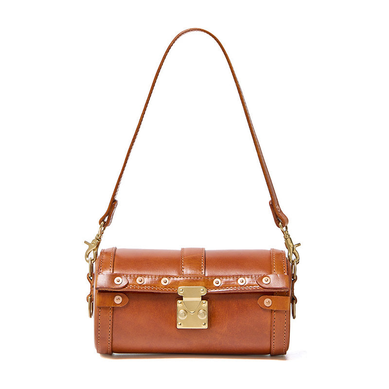 Vegetable tanned leather barrel bag in brown with metal latch lock and dual detachable adjustable straps