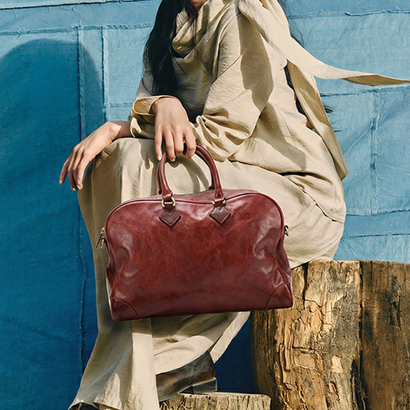 Brown vegetable-tanned leather overnight bag with dual handles and detachable shoulder strap