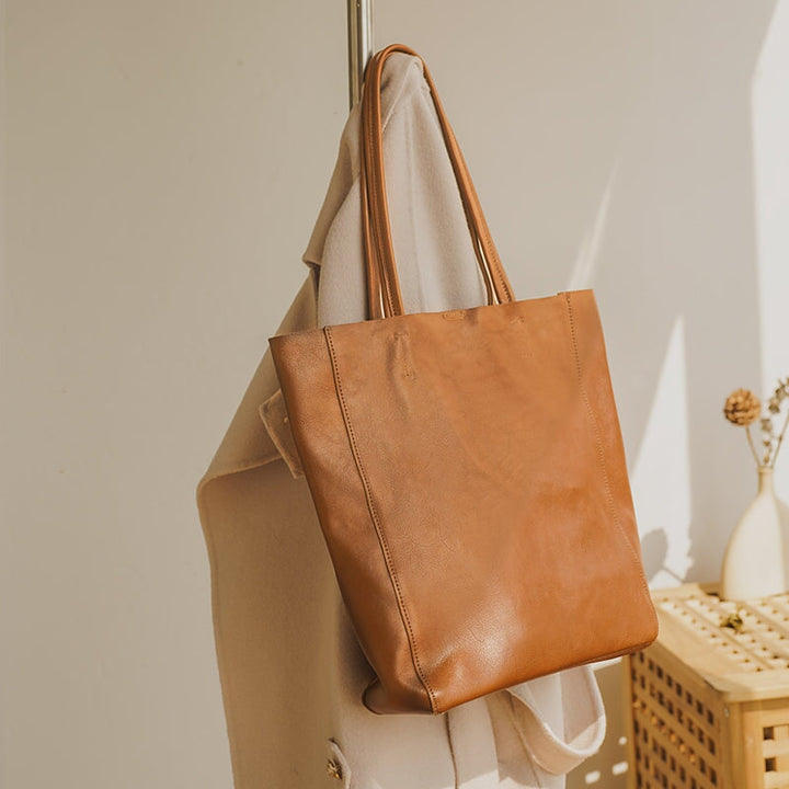 Brown vintage leather tote bag resting on a wooden rack