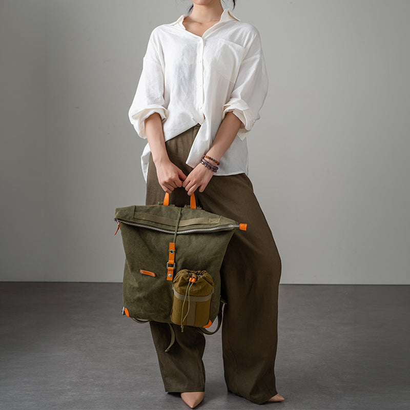 Olive waxed canvas roll-top backpack with leather trim, carried by hand