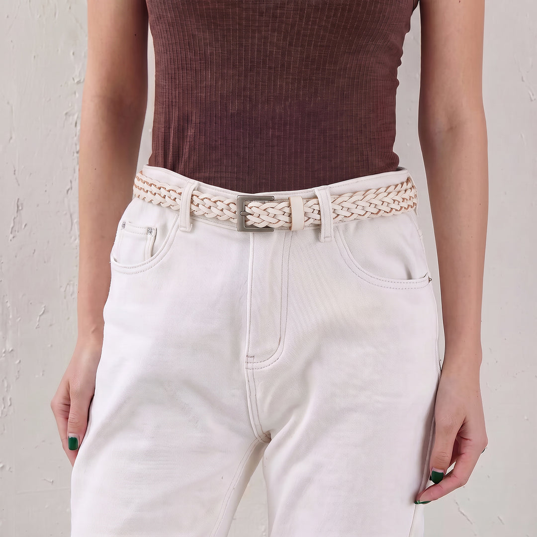 Woman wearing a white braided leather belt with high-waisted trousers.