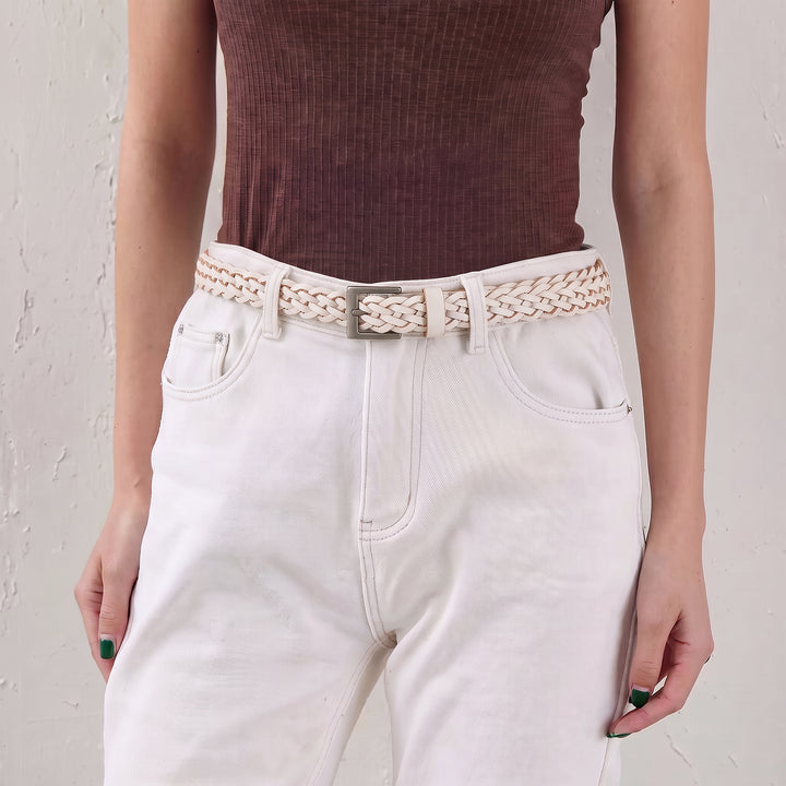 Woman wearing a white braided leather belt with high-waisted trousers.