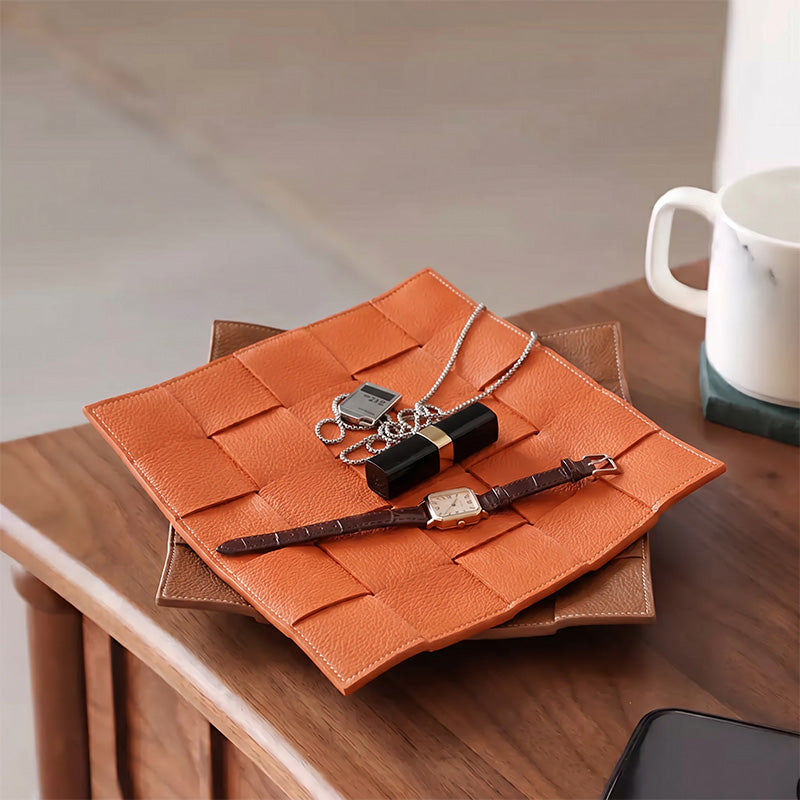 Woven leather valet tray in orange styled on a wooden nightstand as a catchall organizer