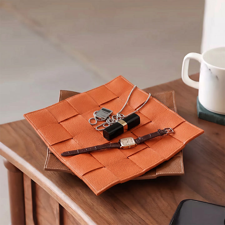 Woven leather valet tray in orange styled on a wooden nightstand as a catchall organizer