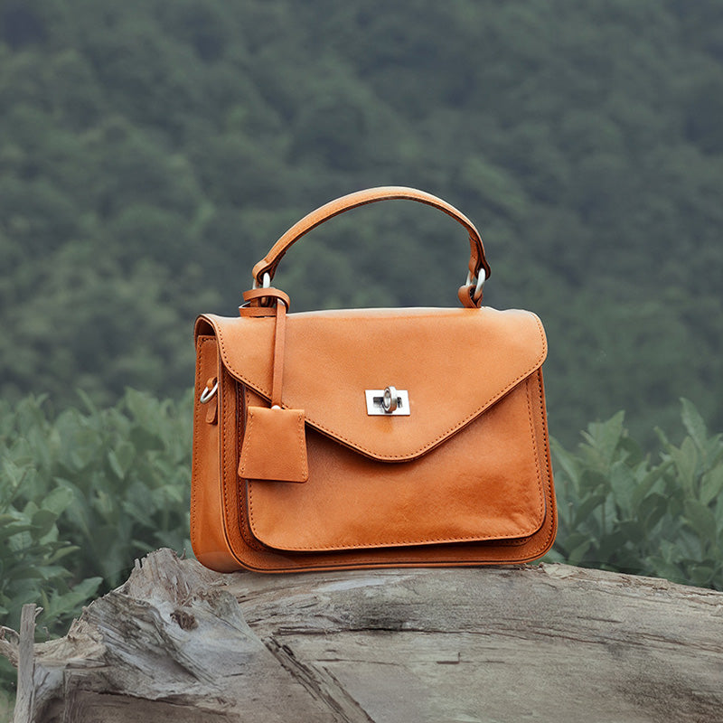 Yellow vegetable tanned leather satchel with gold twist-lock closure and detachable crossbody strap