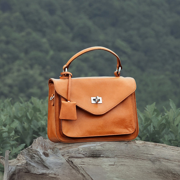 Yellow vegetable tanned leather satchel with gold twist-lock closure and detachable crossbody strap